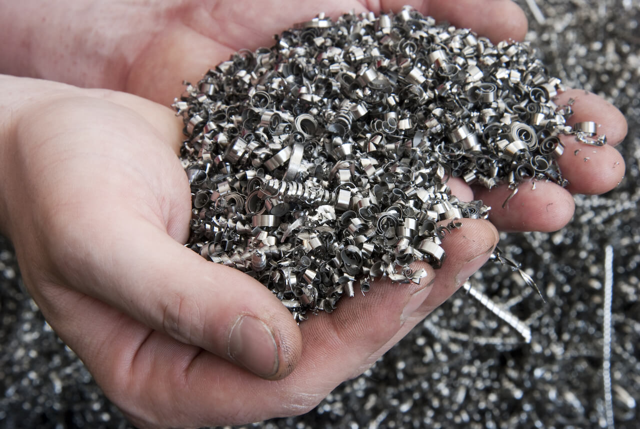 Two hands holding small metallic pieces, possibly for assembly or inspection in a manufacturing or craft setting.