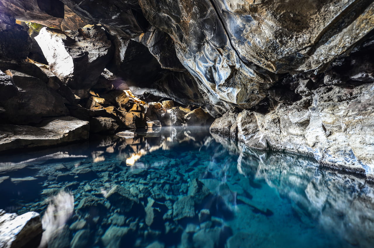 A cave with a tranquil pool of water, creating a serene and natural underground environment.