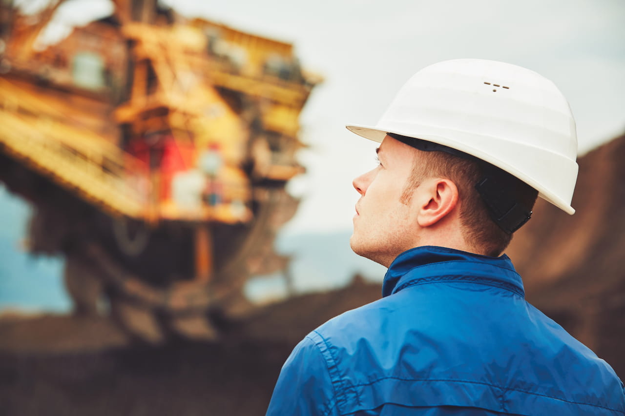 An engineer reviewing a project plan in an industrial setting, focused on overseeing or managing operations.