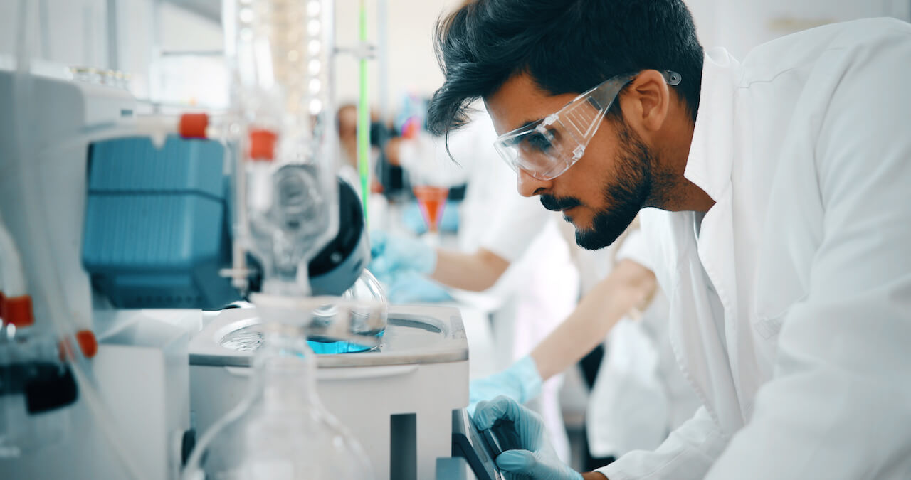 Scientist in a laboratory examining a microscope, engaged in research or analysis.