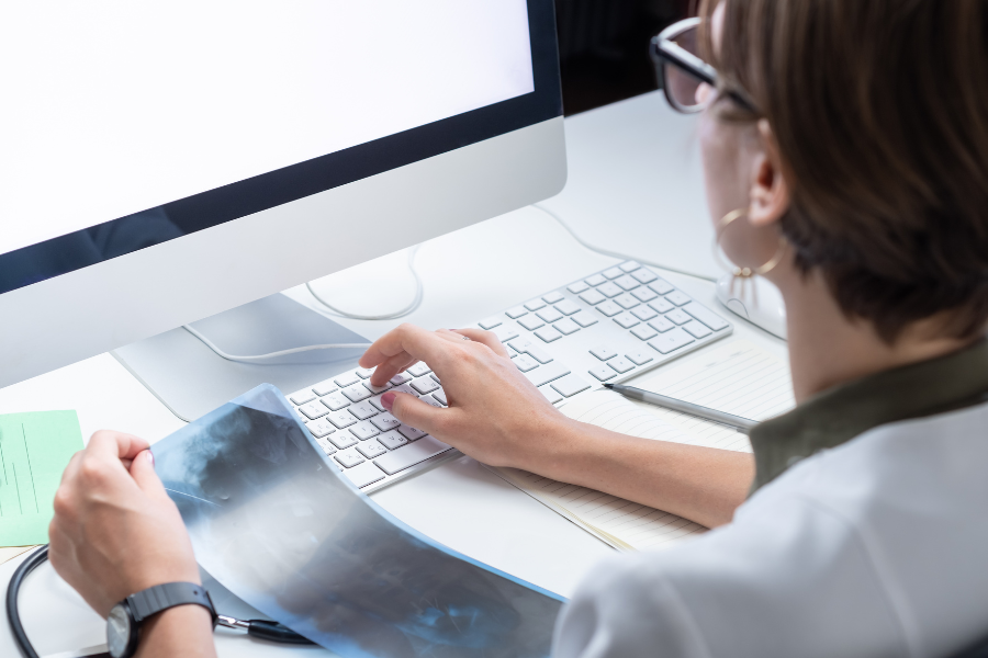 A person holding an X-ray sheet in one hand while using a computer.