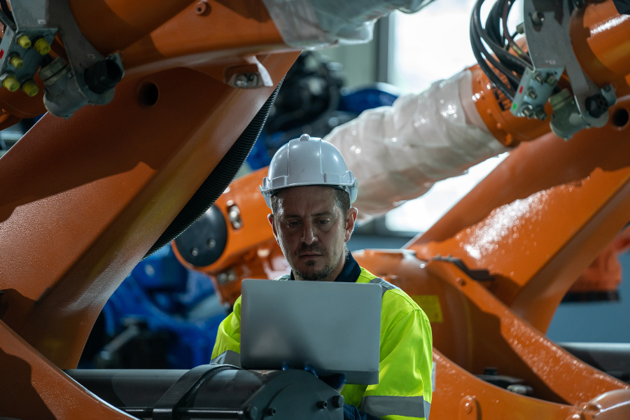 Worker using an iPad to monitor production metrics in a manufacturing environment.