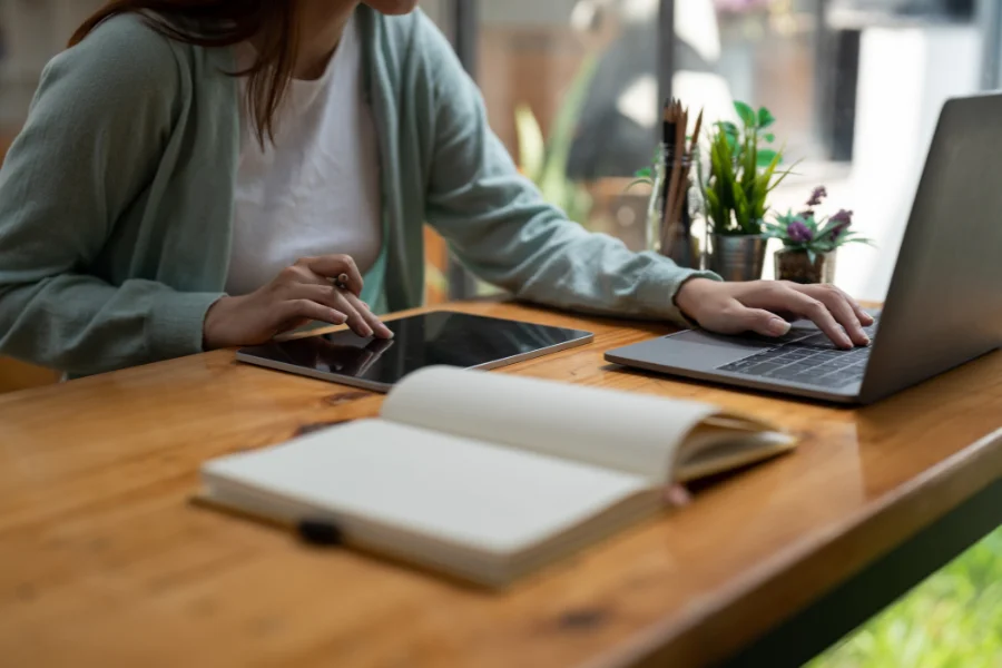 a person sitting at a table with a laptop and notebook