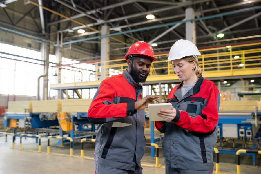 workers in hard hats looking at a tablet in a factory