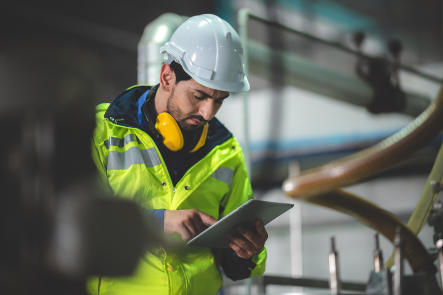 a person in a safety vest is using a tablet in a factory
