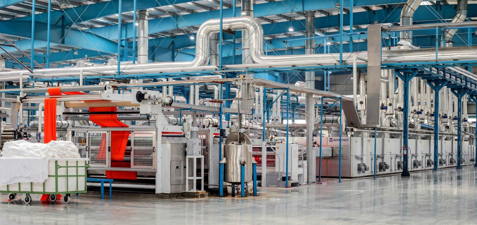 Interior of a factory with large industrial tubes and machinery.