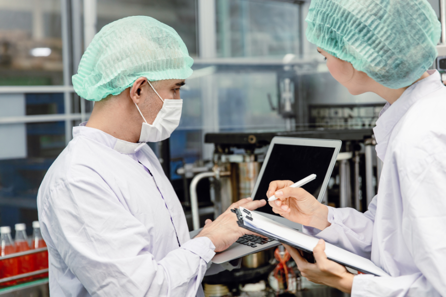 two people in white lab coats working in a factory