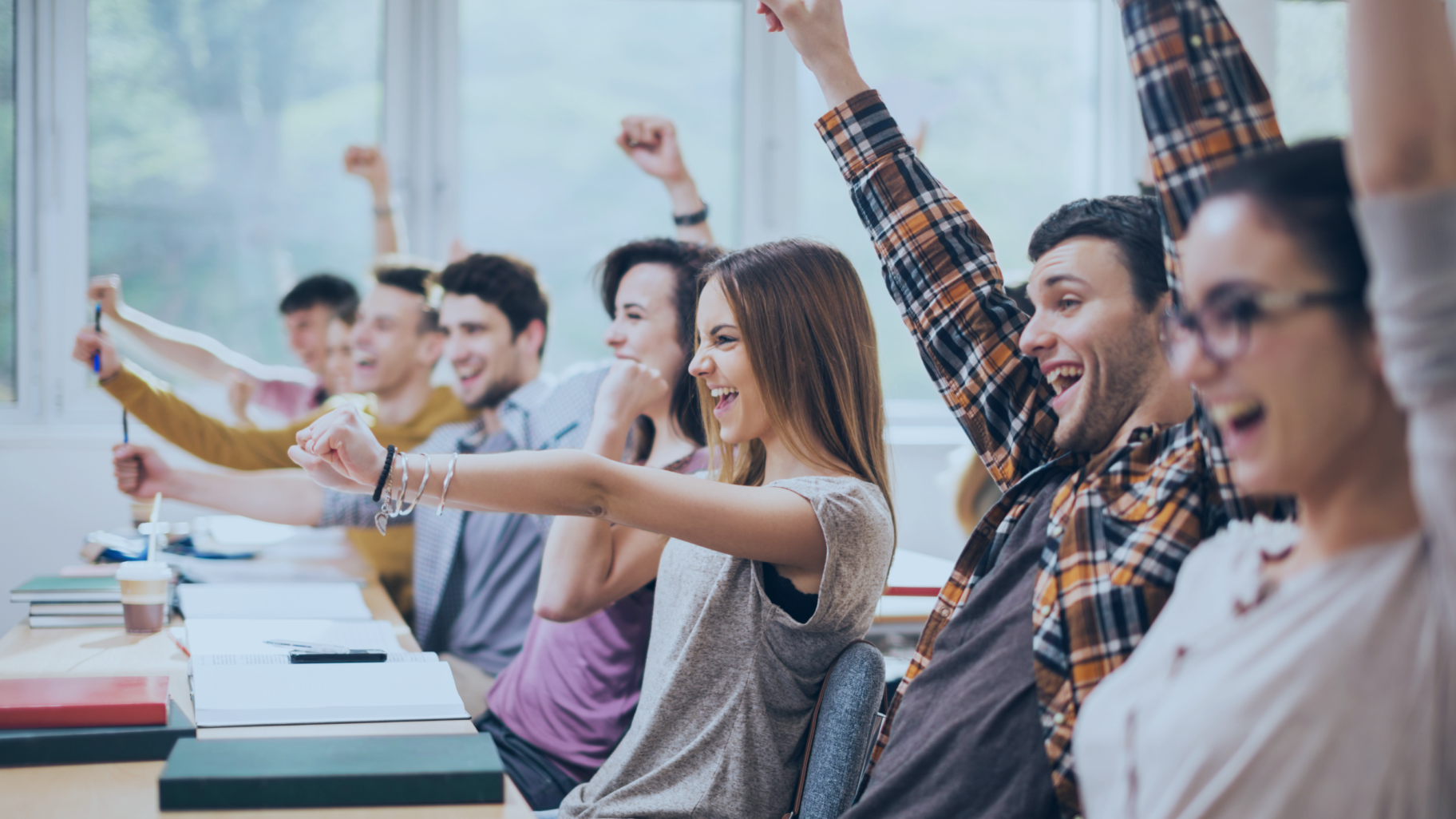 a group of students raising their hands in the classroom
