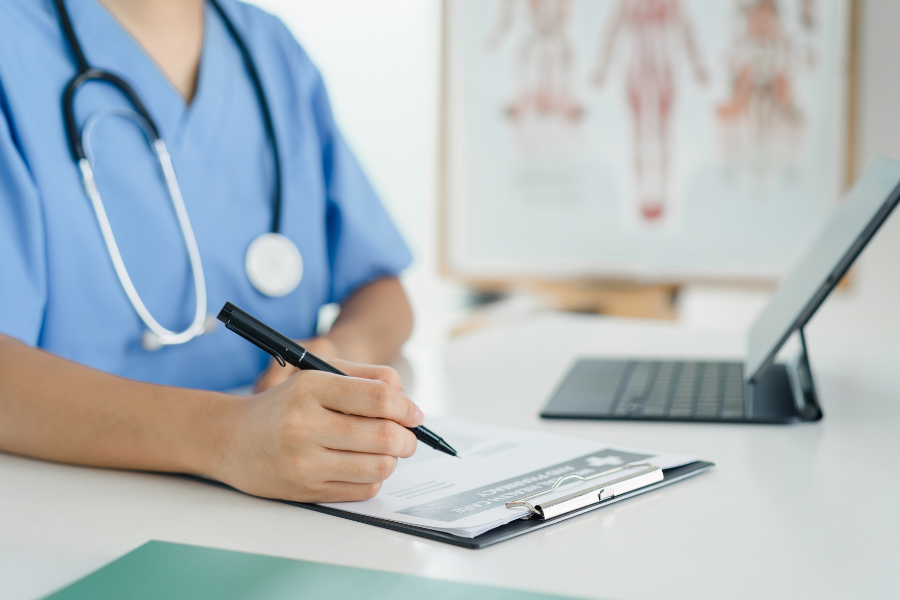 A doctor is writing on a piece of paper while sitting at a desk