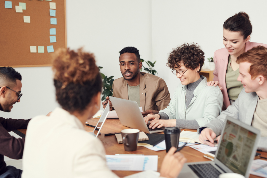 a group of people sitting around a table looking at a laptop