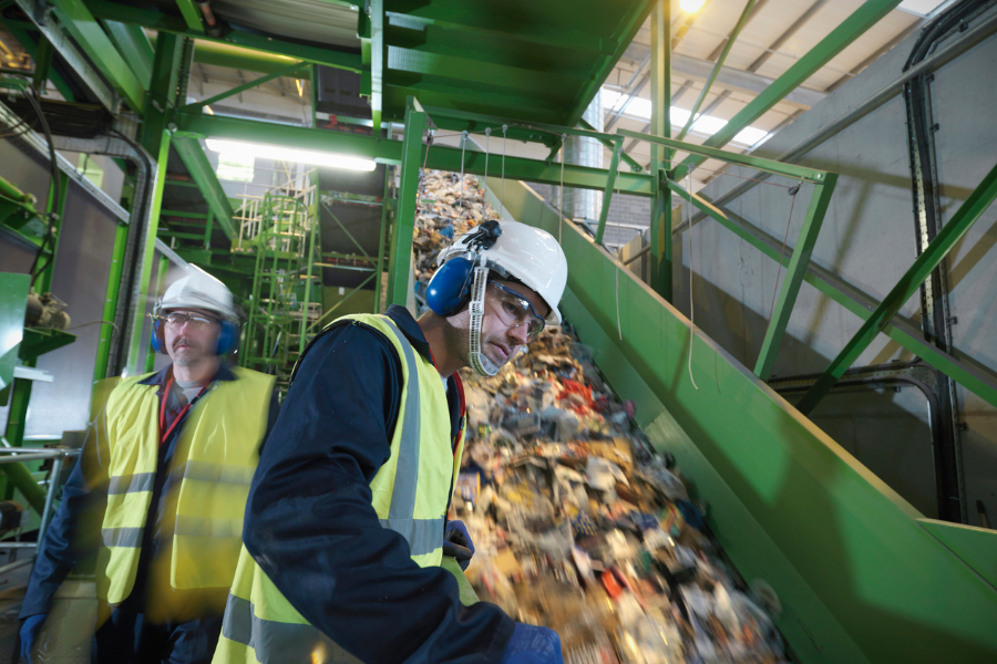 two workers are standing in front of a conveyor belt