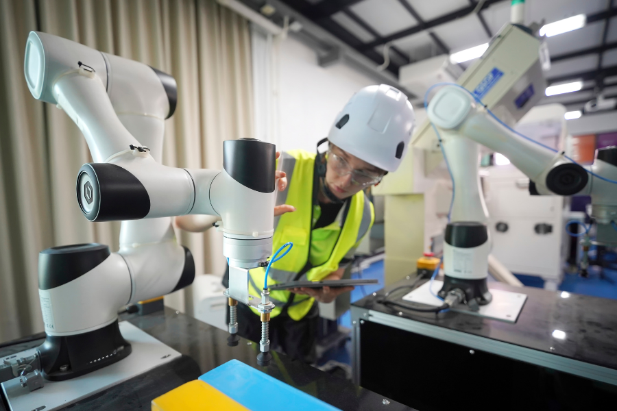 A person working on a robotic arm in a factory